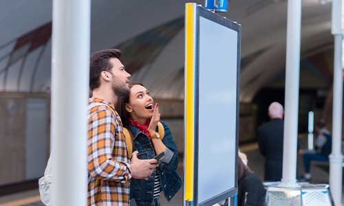 un hombre y una mujer viendo interesados una señalización digital.